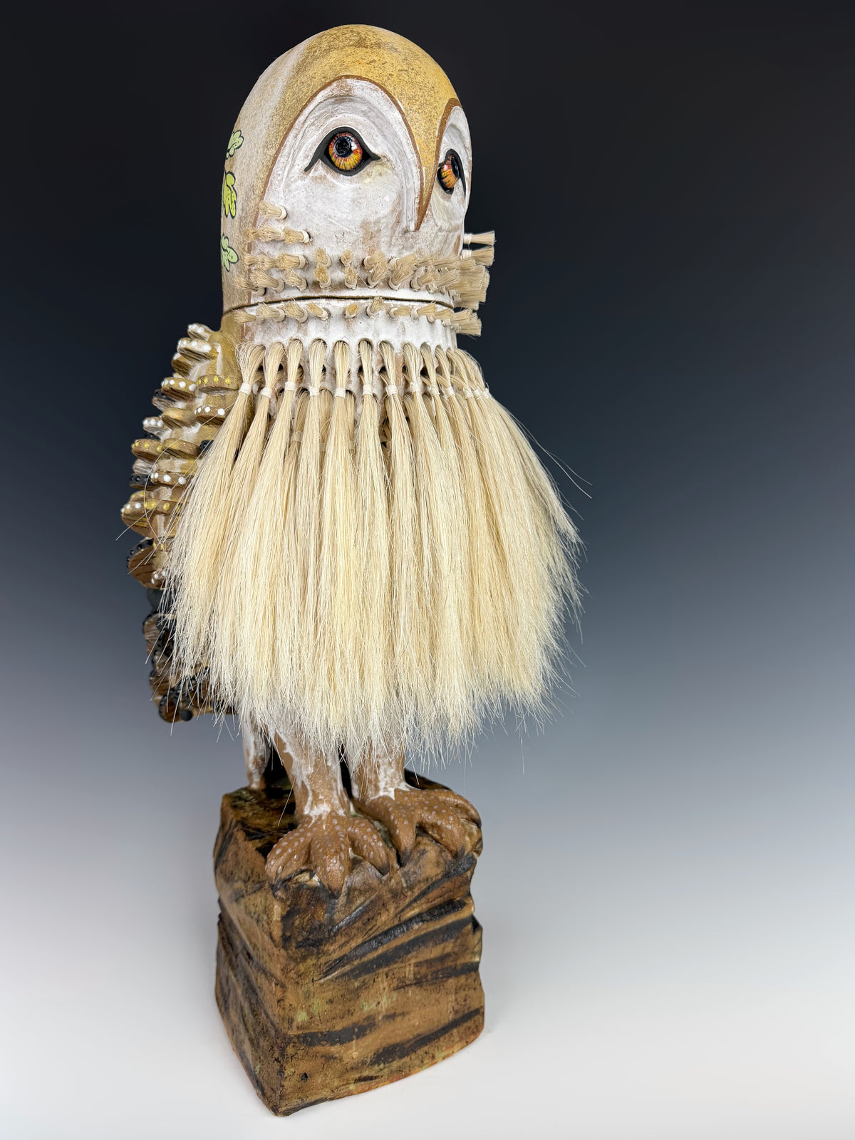 Artist: Jennifer Rosseter; A sculptural owl perched on a post, with white horse hair plumage, detailed painted facial features, and stylized, dimensional feather detail.