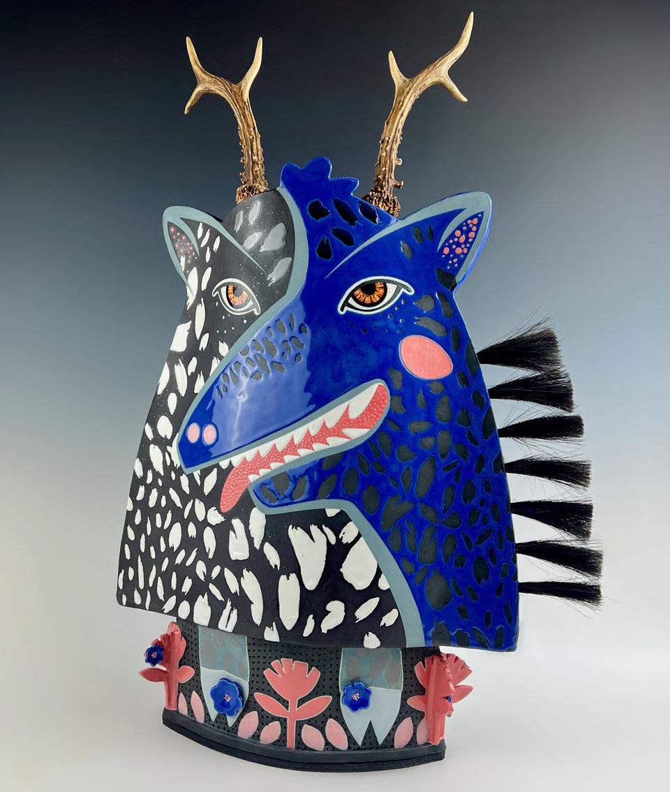 Artist: Jennifer Rosseter; Porcelain sculptural art piece depicting a split face, good and evil, day and night, pattern, antlers, and horse hair accents with a decorative base.,